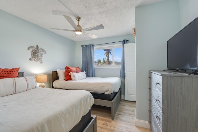 bedroom with light wood-style floors, ceiling fan, a textured ceiling, and baseboards