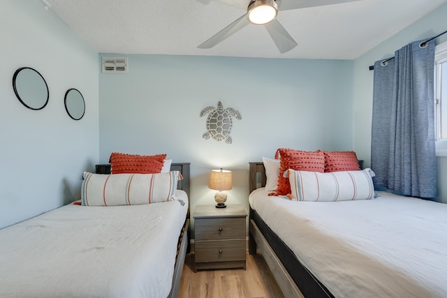 bedroom with light wood-style flooring, visible vents, and a ceiling fan