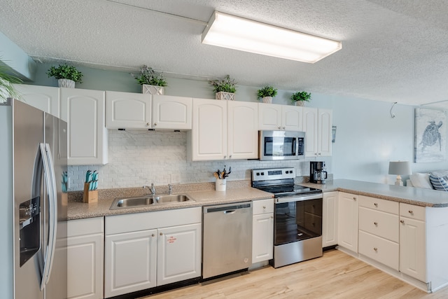 kitchen with stainless steel appliances, light wood-type flooring, a sink, and white cabinetry