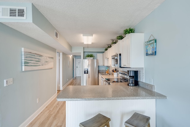 kitchen with a peninsula, visible vents, stainless steel appliances, and light countertops