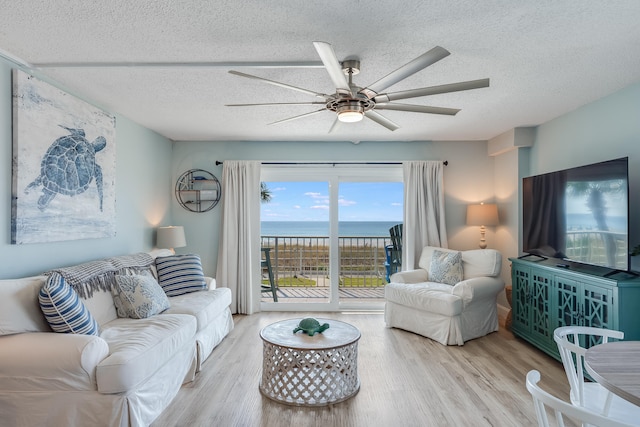 living area featuring a textured ceiling, a ceiling fan, and wood finished floors