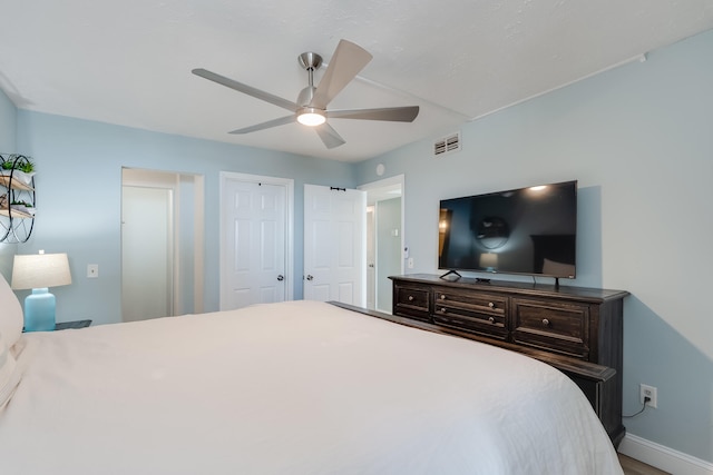 bedroom featuring multiple closets, baseboards, visible vents, and a ceiling fan