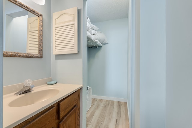 bathroom featuring a textured ceiling, wood finished floors, vanity, and baseboards