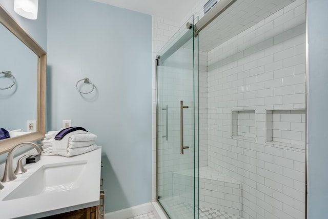 bathroom with a shower stall, vanity, and baseboards