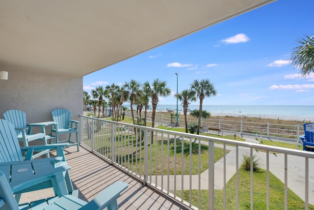 balcony with a water view and a view of the beach