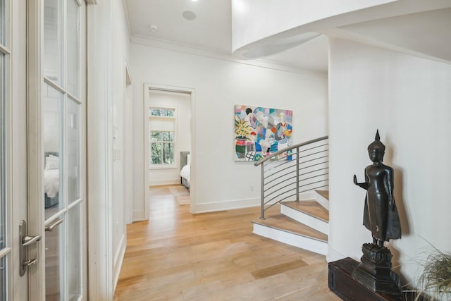 interior space featuring stairway, light wood-style flooring, baseboards, and ornamental molding