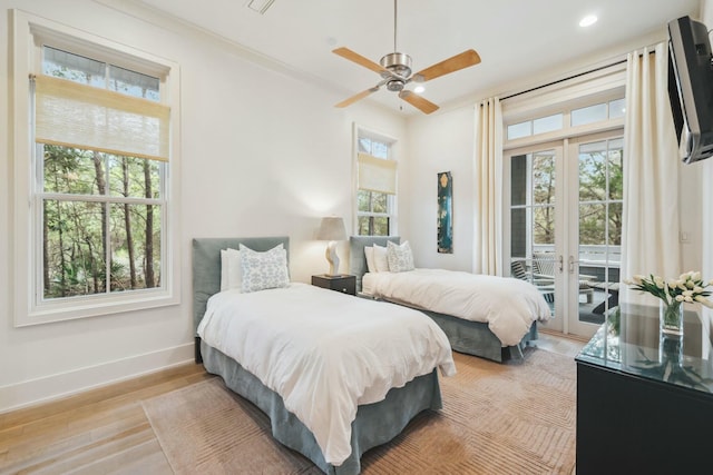 bedroom with wood finished floors, baseboards, multiple windows, and access to exterior