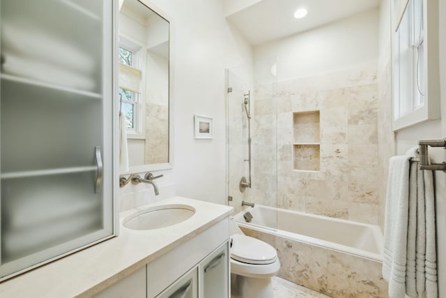 bathroom with toilet, vanity, and tiled shower / bath