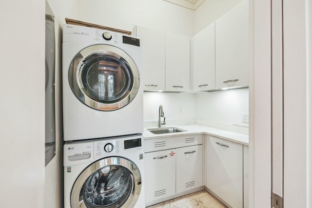 clothes washing area with cabinet space, stacked washer / drying machine, and a sink