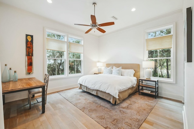 bedroom featuring visible vents, light wood-style flooring, multiple windows, and ornamental molding