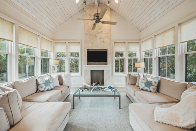 sunroom / solarium featuring lofted ceiling, a ceiling fan, wooden ceiling, and a fireplace