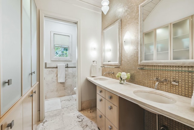 bathroom featuring double vanity, marble finish floor, toilet, and a sink