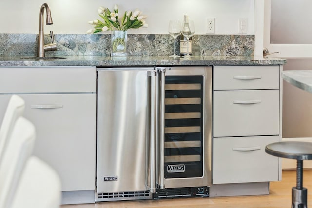 interior space featuring a sink, wine cooler, a bar, and wood finished floors