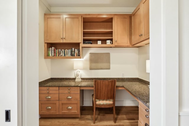 office with light wood-style flooring and built in desk