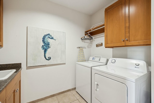 washroom with baseboards, light tile patterned flooring, cabinet space, separate washer and dryer, and a sink