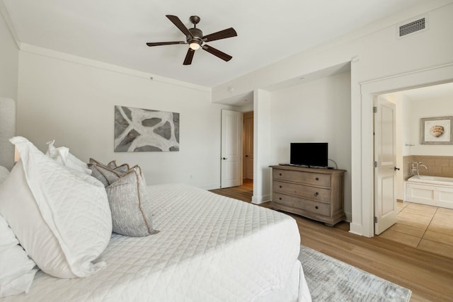 bedroom with visible vents, ornamental molding, a ceiling fan, ensuite bathroom, and wood finished floors