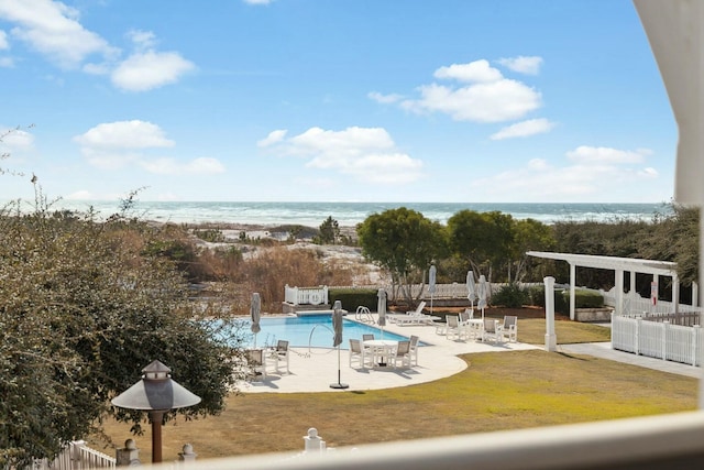 pool with a patio area, a water view, and fence