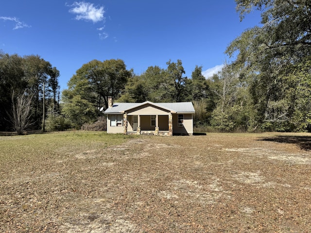 exterior space with covered porch, a chimney, and metal roof