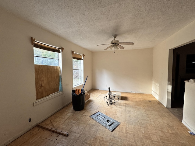 unfurnished room with baseboards, a ceiling fan, and a textured ceiling