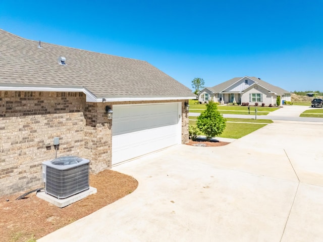 view of property exterior featuring a lawn, cooling unit, concrete driveway, and roof with shingles