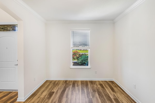 empty room featuring ornamental molding, wood finished floors, and baseboards