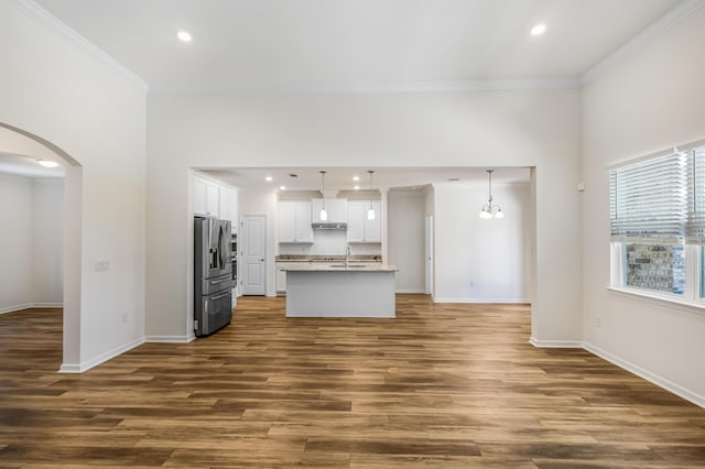 unfurnished living room featuring arched walkways, dark wood-style flooring, crown molding, recessed lighting, and baseboards