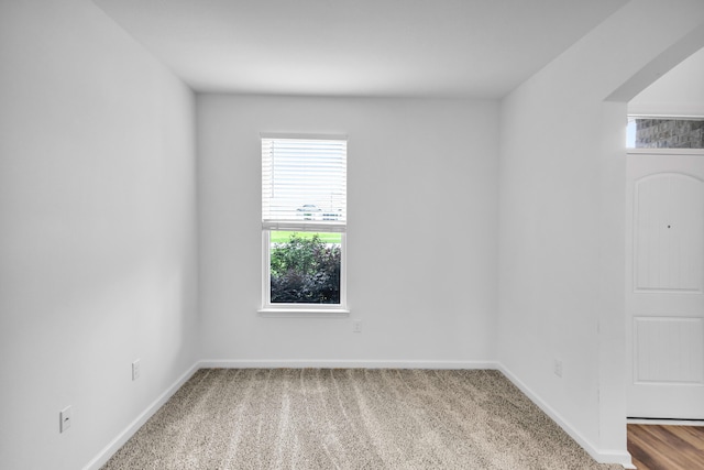 carpeted empty room featuring baseboards