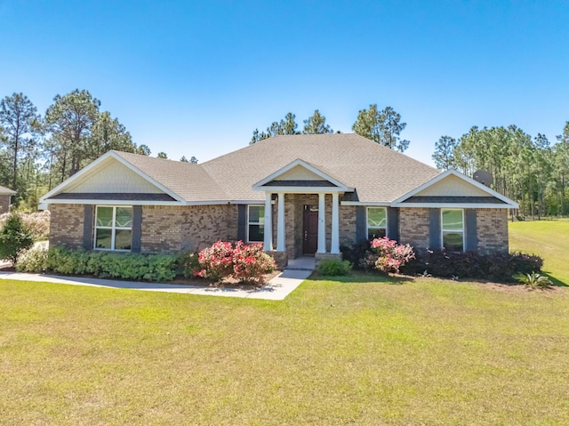 view of front of house featuring brick siding, a front lawn, and roof with shingles