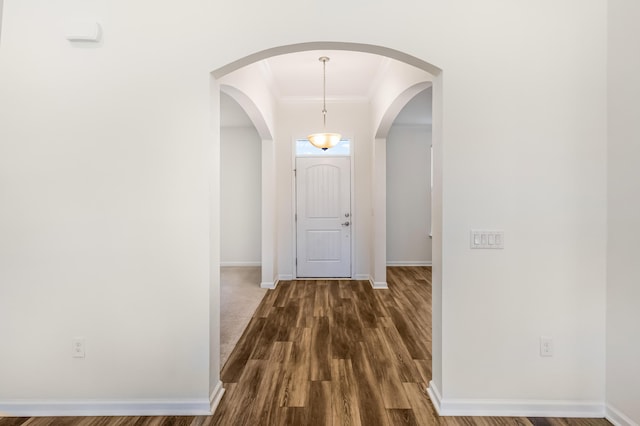 interior space with dark wood-type flooring, ornamental molding, and baseboards