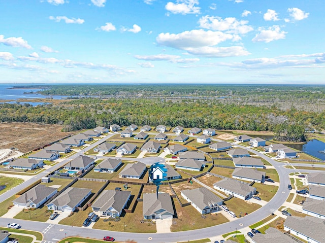 drone / aerial view with a wooded view, a residential view, and a water view