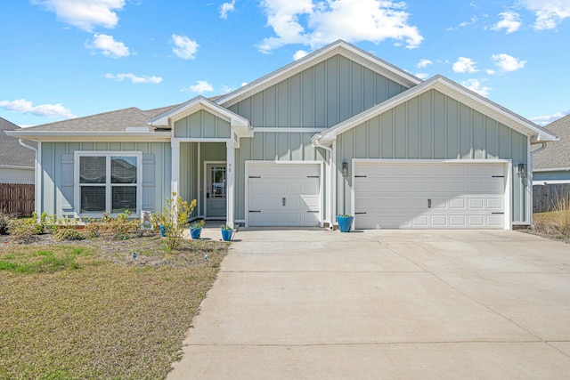 view of front of property featuring a shingled roof, concrete driveway, a garage, and fence