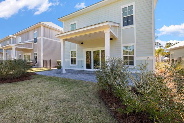 rear view of property with a lawn, board and batten siding, and a patio