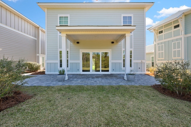 back of house featuring a patio area, board and batten siding, and a yard