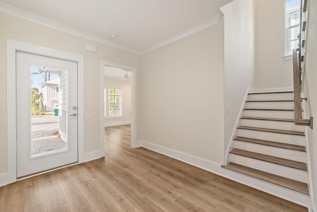 foyer entrance featuring stairs, baseboards, light wood finished floors, and ornamental molding