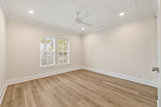 spare room with baseboards, light wood-style floors, attic access, and ornamental molding