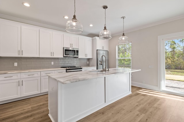 kitchen with tasteful backsplash, ornamental molding, light wood-style floors, stainless steel appliances, and a sink