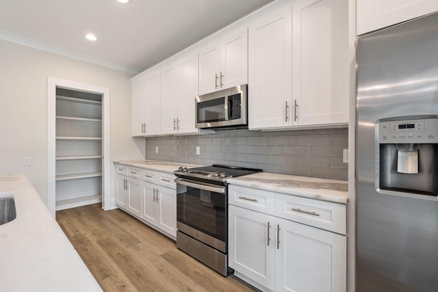 kitchen featuring light countertops, decorative backsplash, light wood-style flooring, appliances with stainless steel finishes, and white cabinets