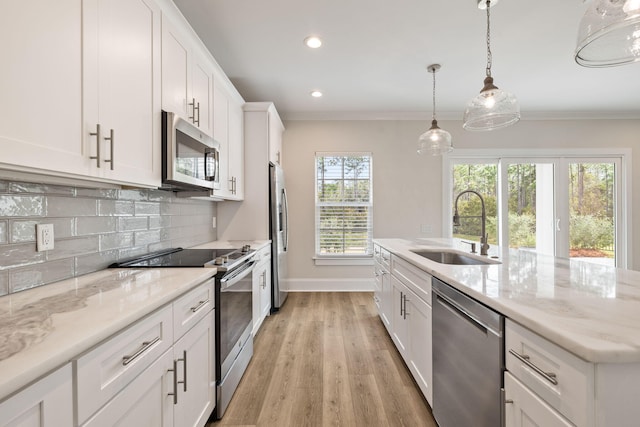 kitchen with backsplash, ornamental molding, stainless steel appliances, white cabinetry, and a sink