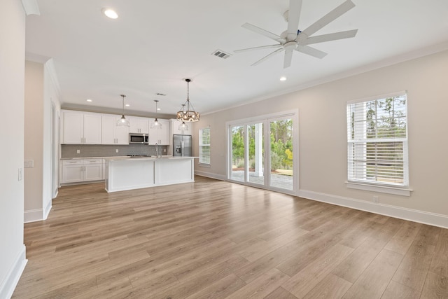 unfurnished living room featuring visible vents, baseboards, light wood-style floors, and crown molding