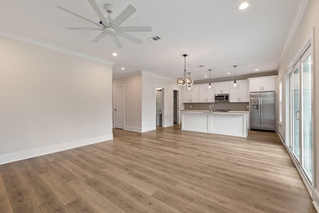 unfurnished living room with visible vents, baseboards, light wood-style floors, and ceiling fan with notable chandelier