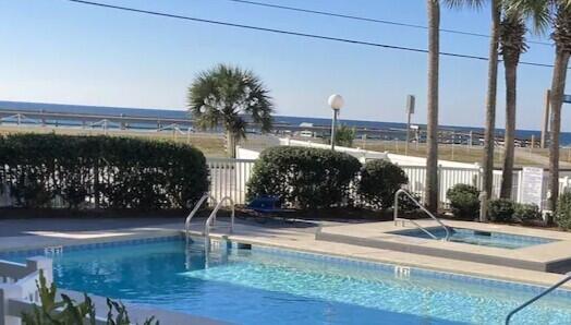 community pool featuring a community hot tub and fence