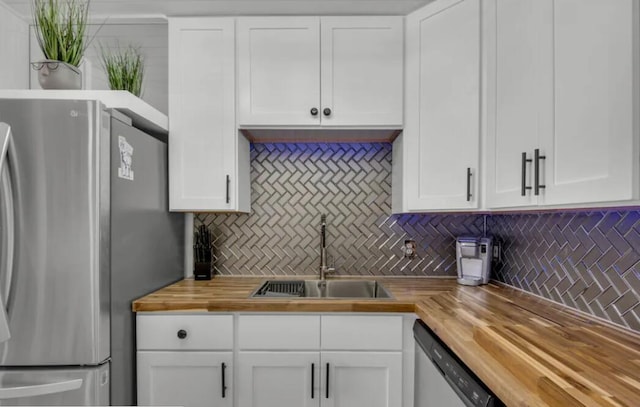 kitchen with white cabinetry, appliances with stainless steel finishes, wooden counters, and a sink