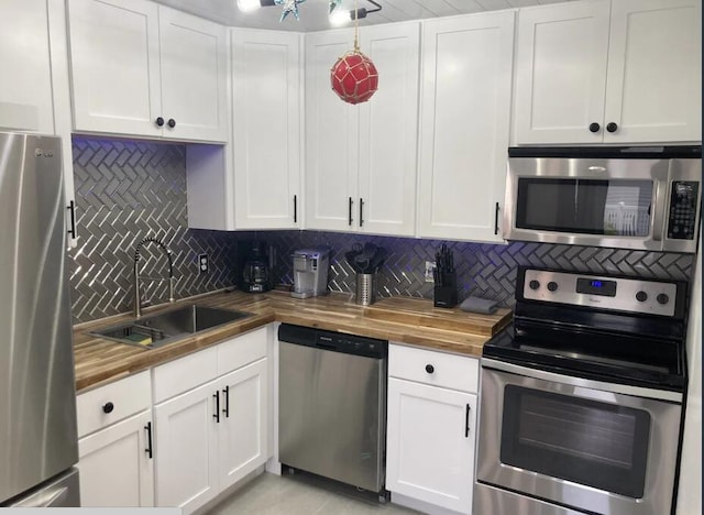 kitchen featuring appliances with stainless steel finishes, a sink, wood counters, and tasteful backsplash