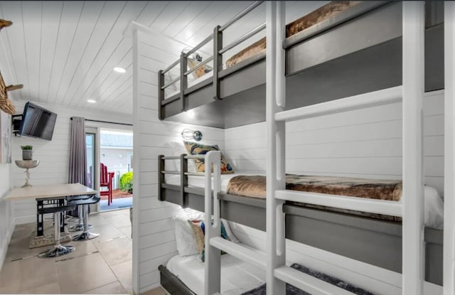 bedroom featuring access to exterior, wood ceiling, light tile patterned flooring, and wooden walls