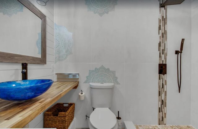 bathroom featuring a tile shower, a sink, and toilet