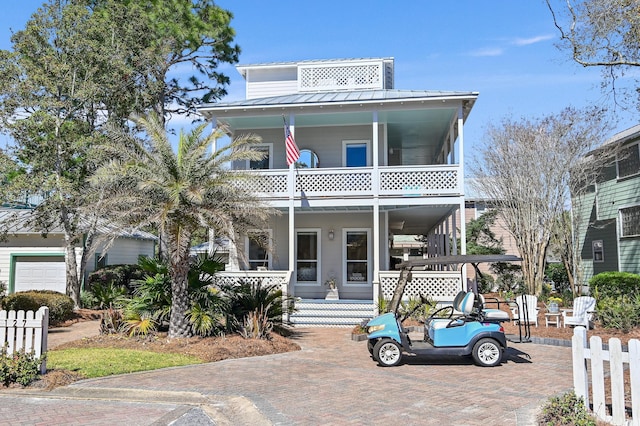 view of front of home featuring a standing seam roof, covered porch, metal roof, and a balcony