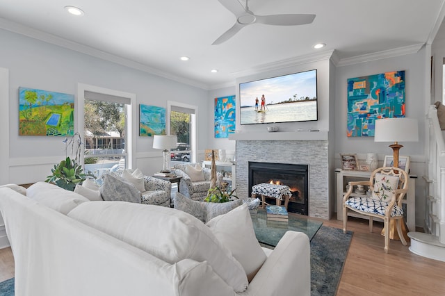 living room featuring crown molding, recessed lighting, a fireplace, and light wood finished floors