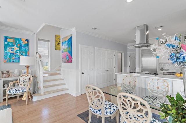 dining area with visible vents, wood finished floors, and ornamental molding