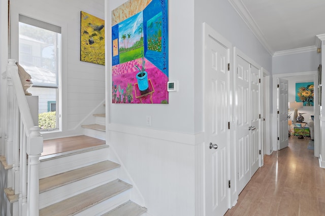 hallway featuring wainscoting, crown molding, stairway, and wood finished floors