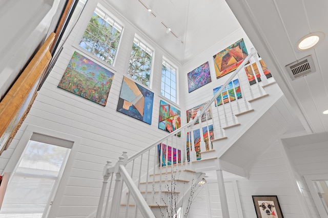 stairway with a towering ceiling, rail lighting, and visible vents